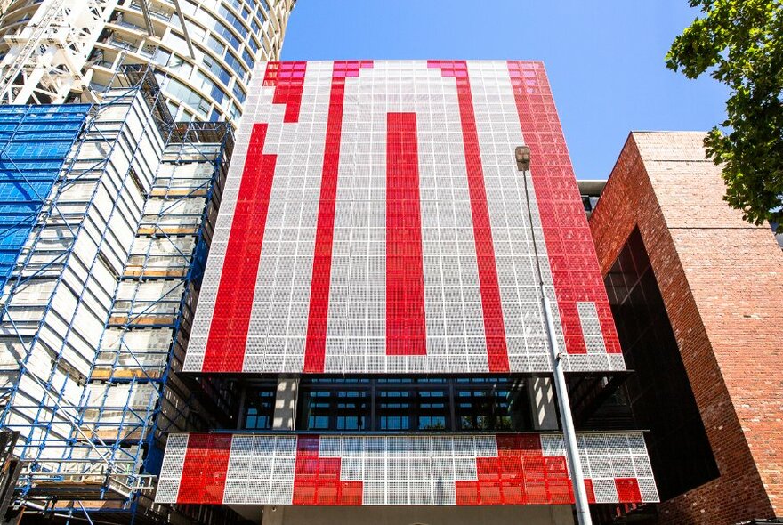 City building showing large scale public artwork spelling out the word NOW on the facade.