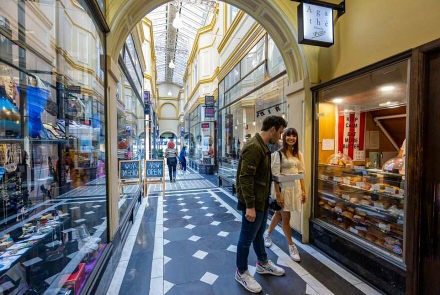 A couple shopping at a small bakery in a laneway