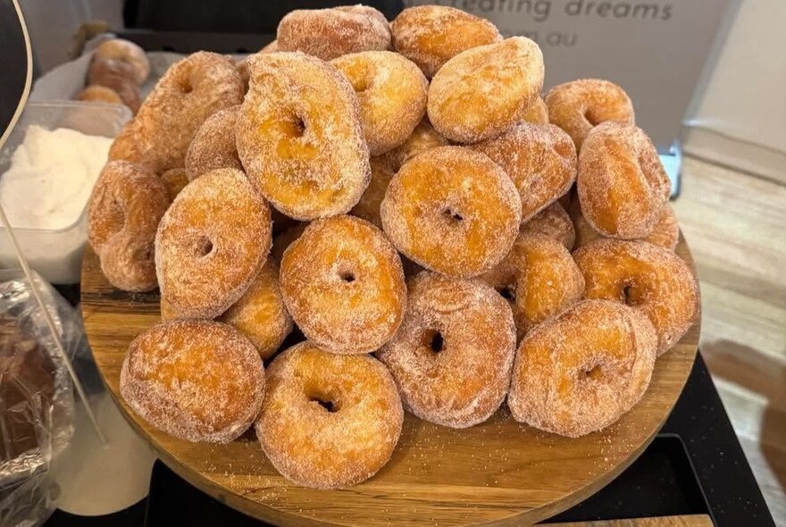 A massive pile of freshly made doughnuts coated with sugar. 