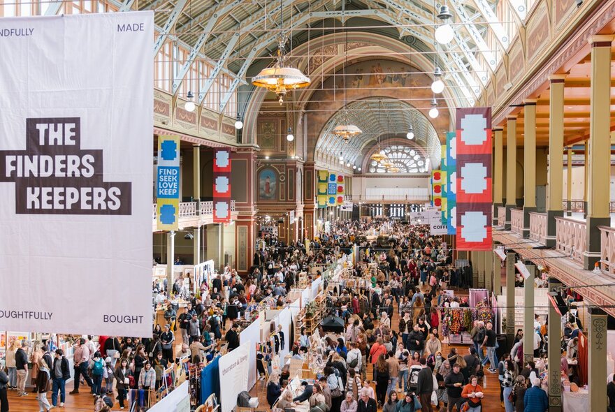 Large crowds of people wandering around stalls at the indoor design market inside the Royal Exhibition Buildings with a white banner hanging from the ceiling that reads THE FINDERS KEEPERS.