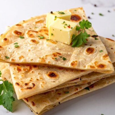 A pile of sourdough flatbread triangles, with two cubes of butter and parsley on top.