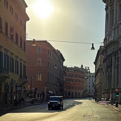 View of a street in Rome on a bright sunny morning, with a single car on the road.