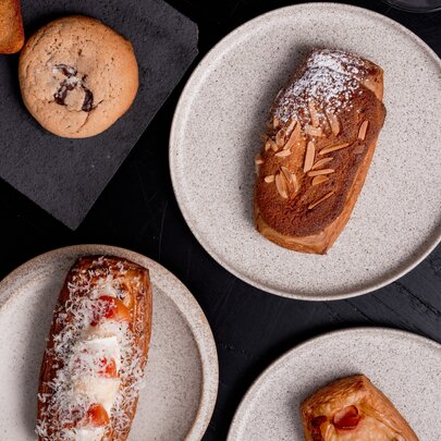 Plates of pastries and cookies on a dark table.