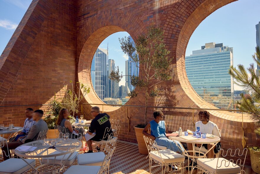 A stylish rooftop bar with cutout windows in the brick wall.