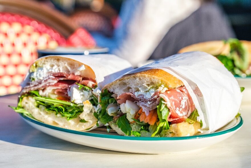 A prosciutto ciabatta with salsa verde, marinated feta, rocket and pickle.