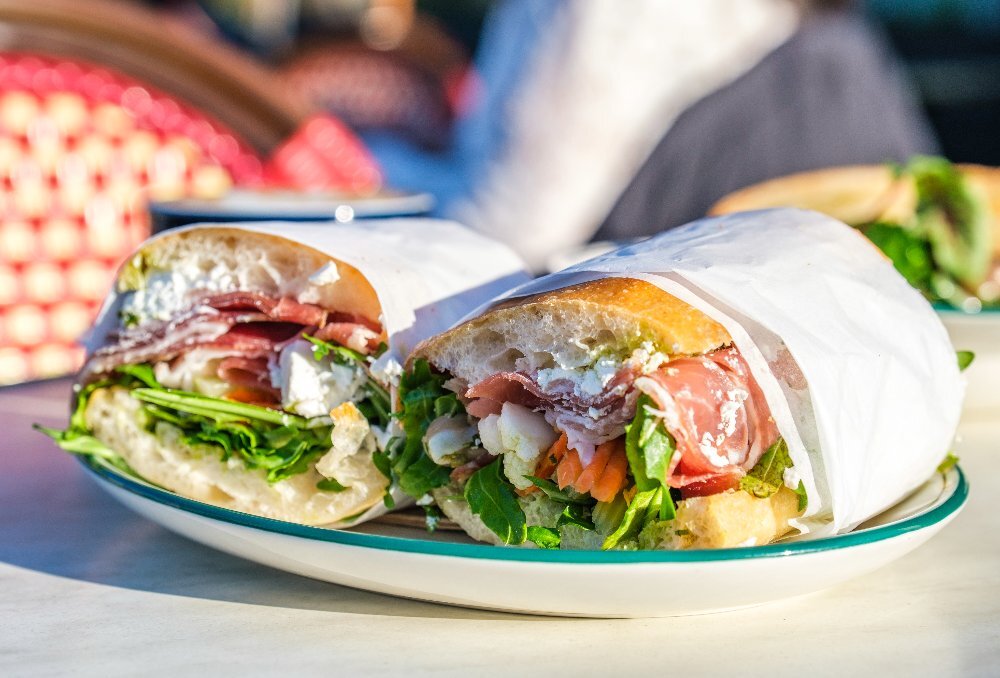 A prosciutto ciabatta with salsa verde, marinated feta, rocket and pickle.