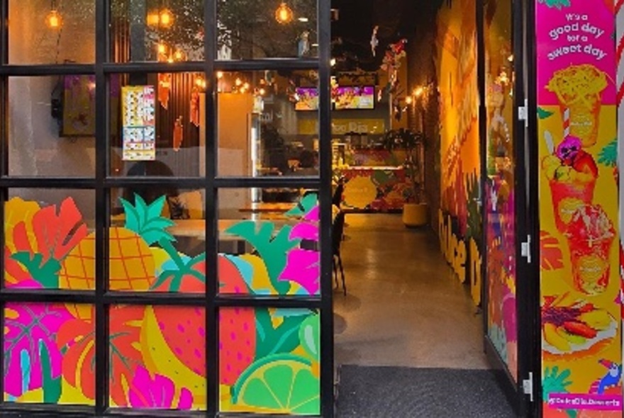 Colourful exterior of a shop with painted images of fruit on the glass window.