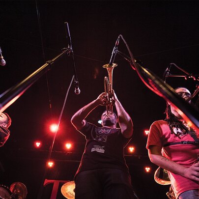 Jazz musicians playing trumpets and sax live on stage.