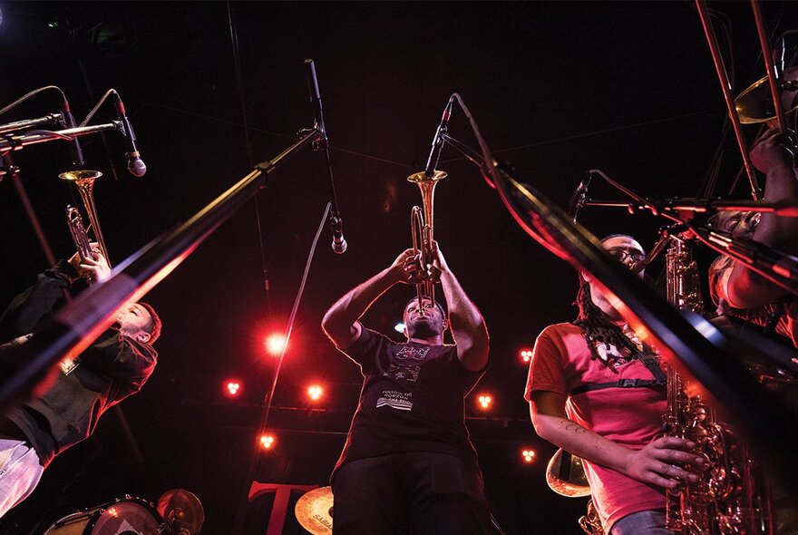 Jazz musicians playing trumpets and sax live on stage.