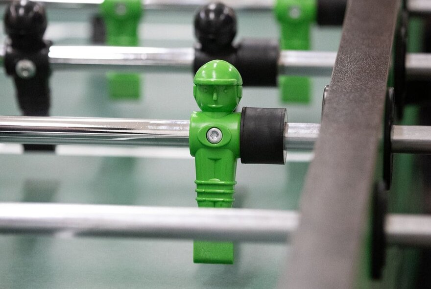 A close-up image of a foosball table with green and black players.