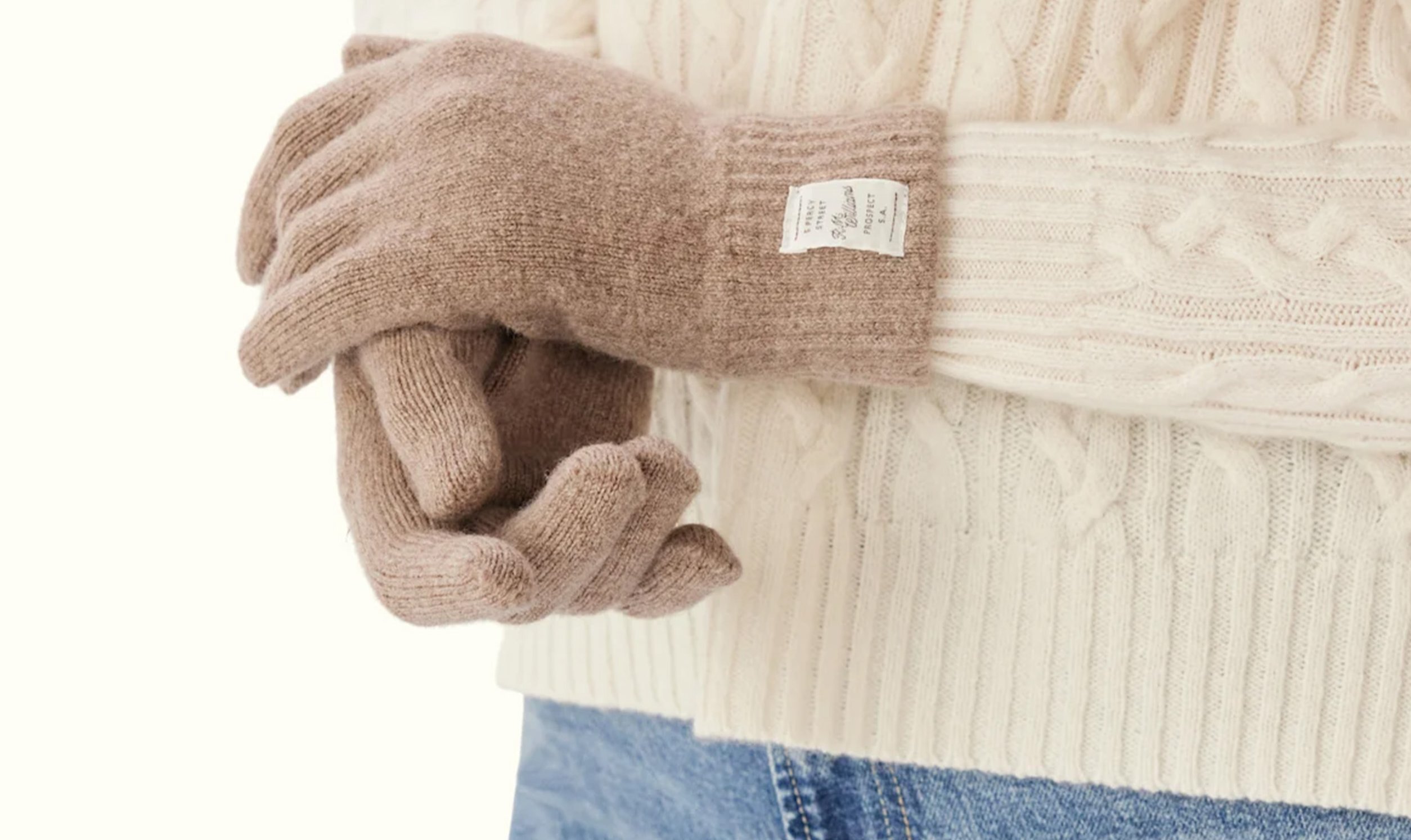 A person is wearing a pair of beige wool gloves.