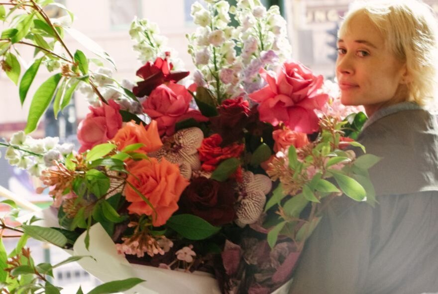 Person holding a huge floral display of roses and blooms.