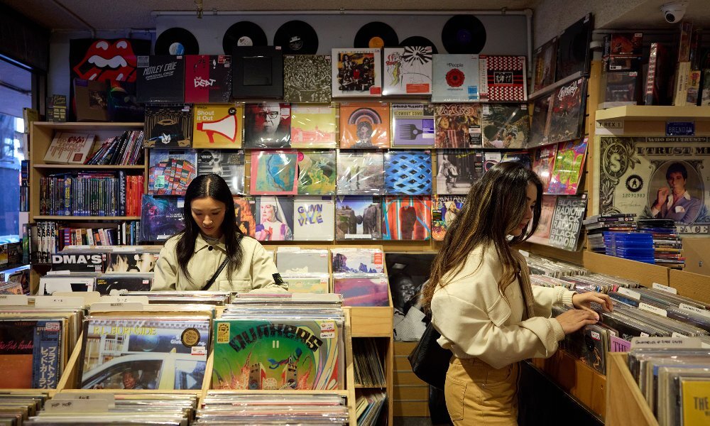 Two friends are browsing through records in a shop.