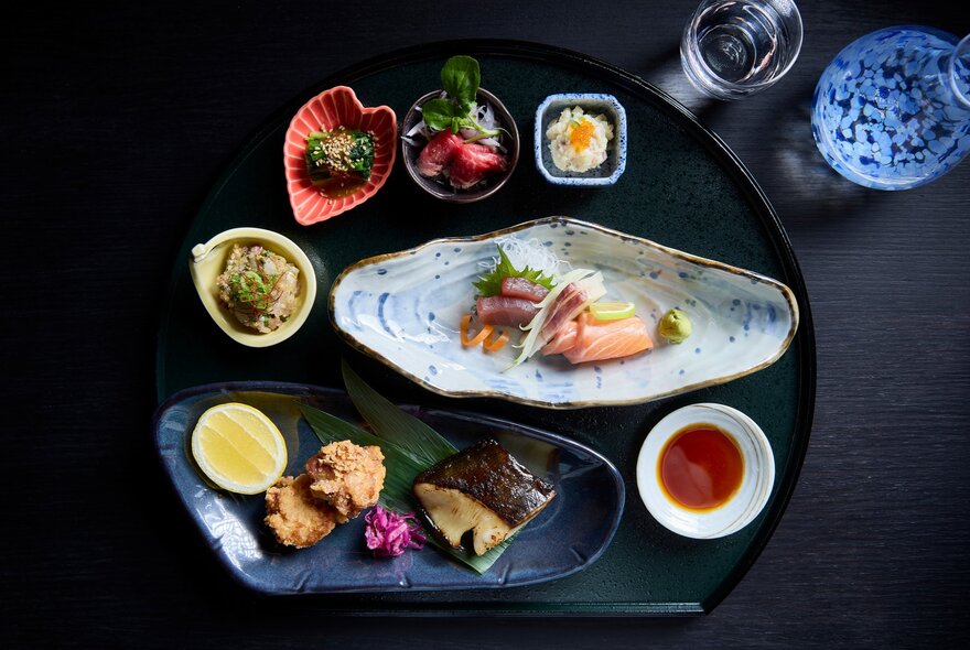Looking down on plates of small Japanese food and condiments. 