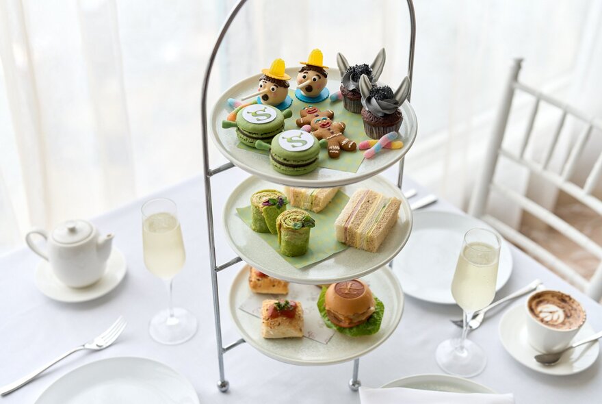 A multi-tiered high tea service featuring finger sandwiches, pastries, and sweets on a classic metal stand, inspired by characters from the movie Shrek.