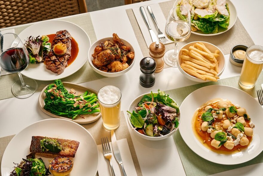 A dinning table laden with plates of food, cutlery and drinks.