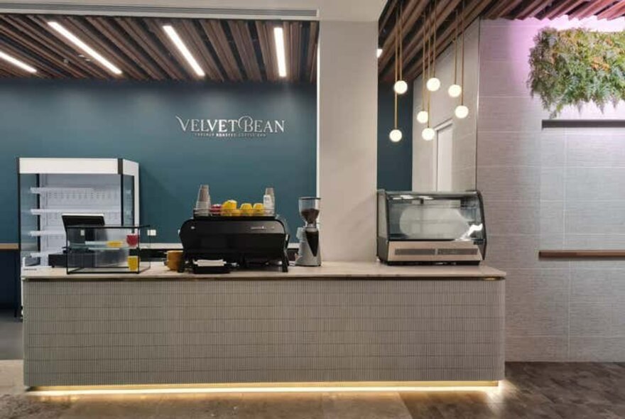 A cafe kiosk with a white-tiled counter and a  dark blue wall. 