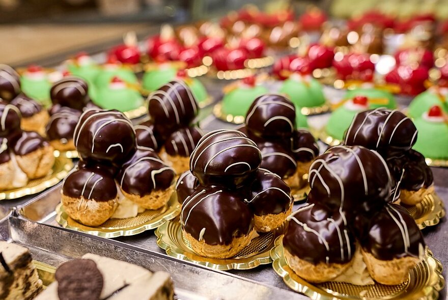 A shelf full of colourful cakes and treats including chocolate profiteroles.