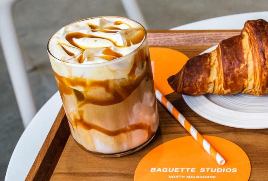 A glass of iced coffee with cream and caramel drizzle through it
