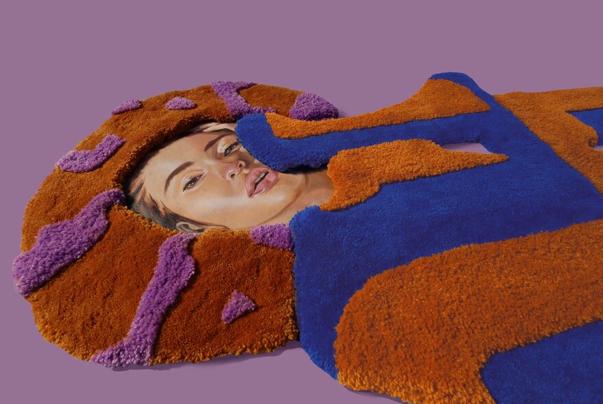 Textile rug design in the shape of a person with an illustration of a woman's face poking through.