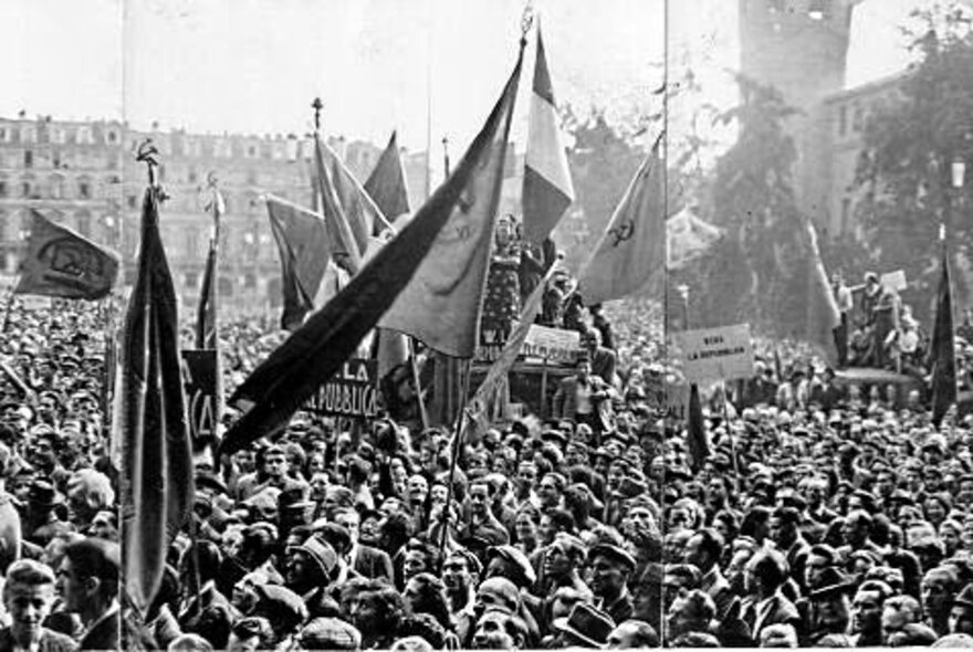 Scenes from the birth of the Italian republic with hundreds of people filling the street and large flags. 