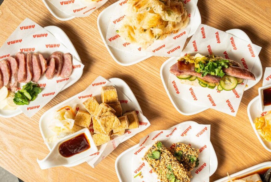 Looking down on a table set with many rectangular plates of food. 