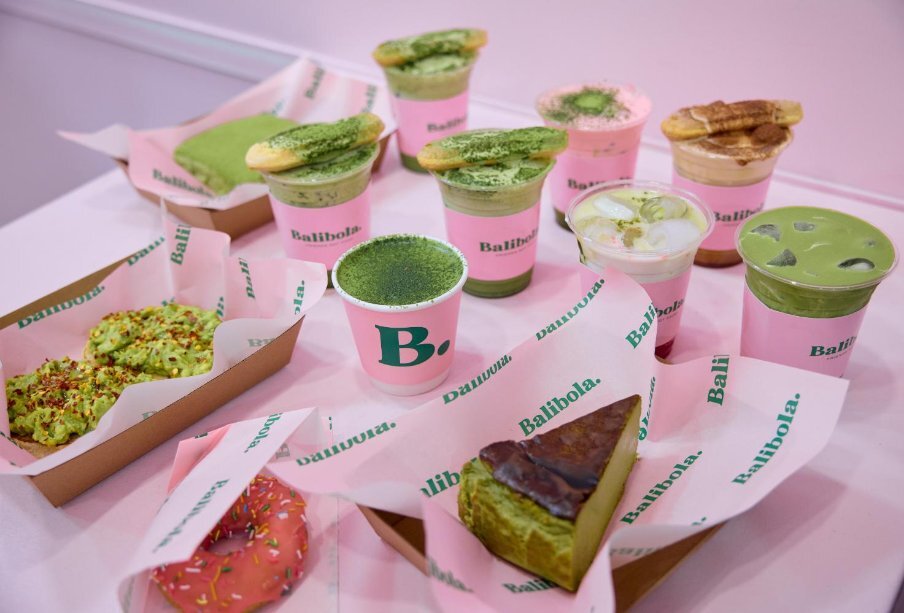 Pink table filled with take away matcha drinks and snacks