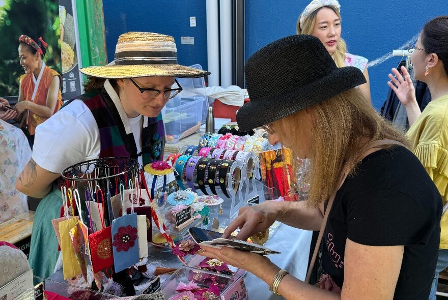 People looking at products at a stall at an outdoor market.
