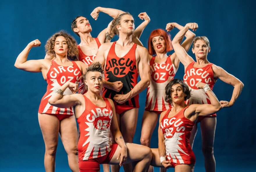 Seven members of Circus Oz posing and flexing their muscles. 