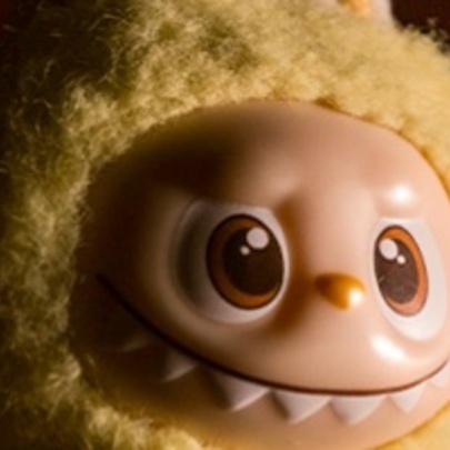 A close up of a troll doll face with a yellow knitted bonnet. 