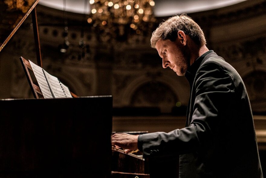 Seated musician playing a keyboard instrument with music.