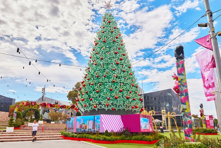 A giant Christmas Tree at Federation Square, with the sky and city buildings in the background. 