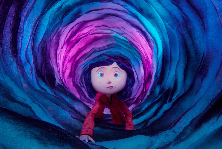 Still from the animation film Coraline, of a young girl with short blue hair and a red top crawling through a vibrant, spiralling tunnel made of swirling blue, purple, and bright pink layers.