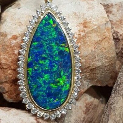 Teadrop-shaped blue and green opal pendant fringed with diamonds.