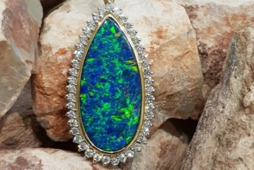 Teadrop-shaped blue and green opal pendant fringed with diamonds.