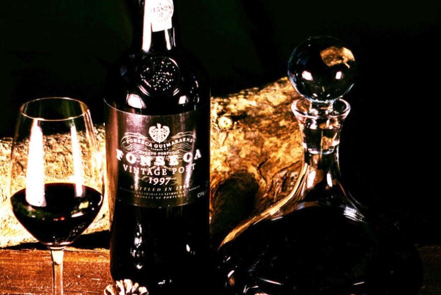 Dark port wine in a glass, a labelled bottle of port and port in a crystal decanter.