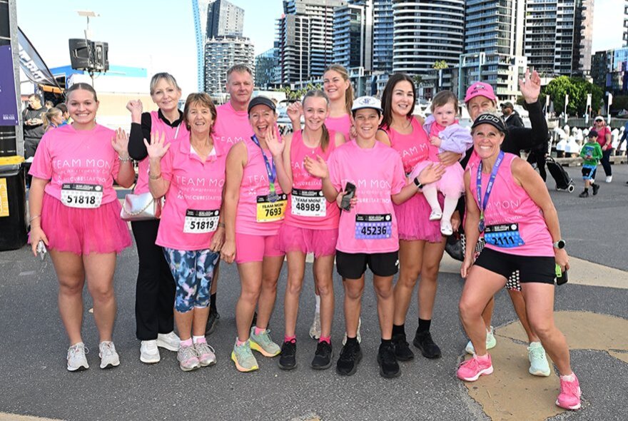 A group of runners in pink posing for a group shot in the city. 