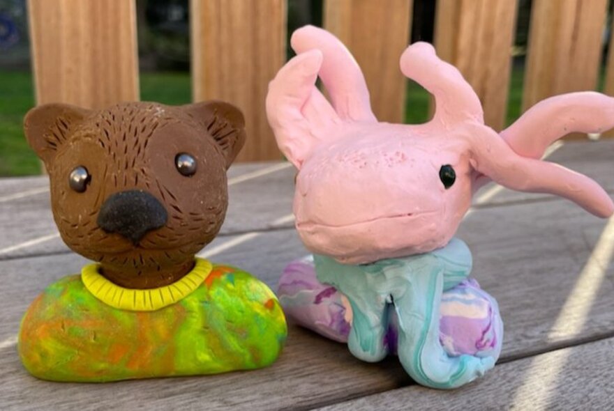 Two small polymer clay animal busts - one a brown bear in a tshirt and the other a pink creature with tentacles.