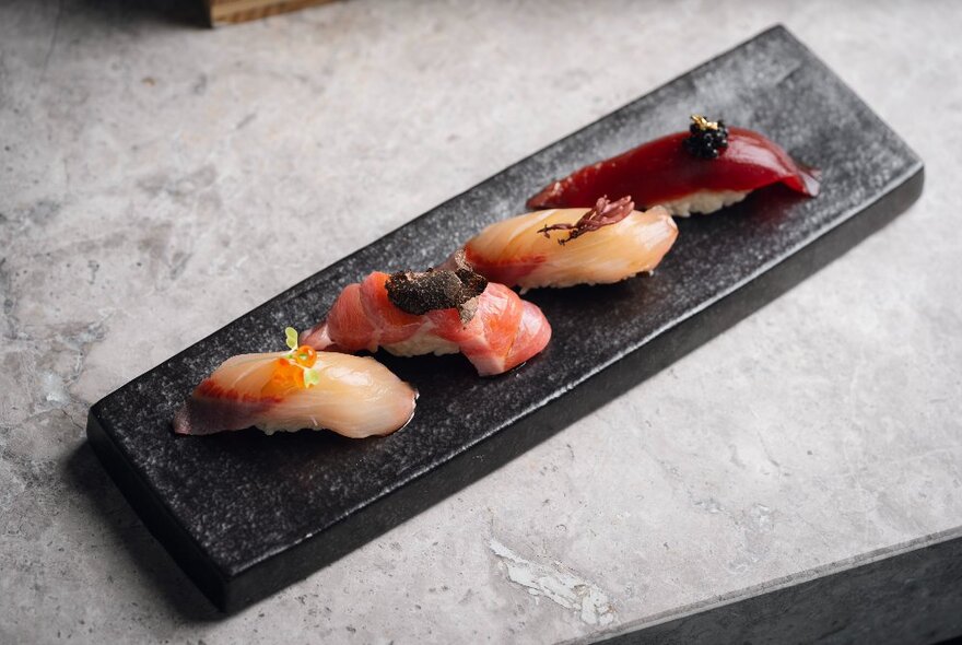 A rectangular plate with four pieces of sushi artfully arranged on it.