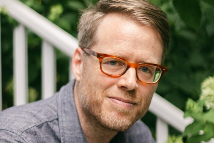 Portrait of American author, Eric Puchner, a man with short blonde hair, tortoiseshell glasses and cropped beard.