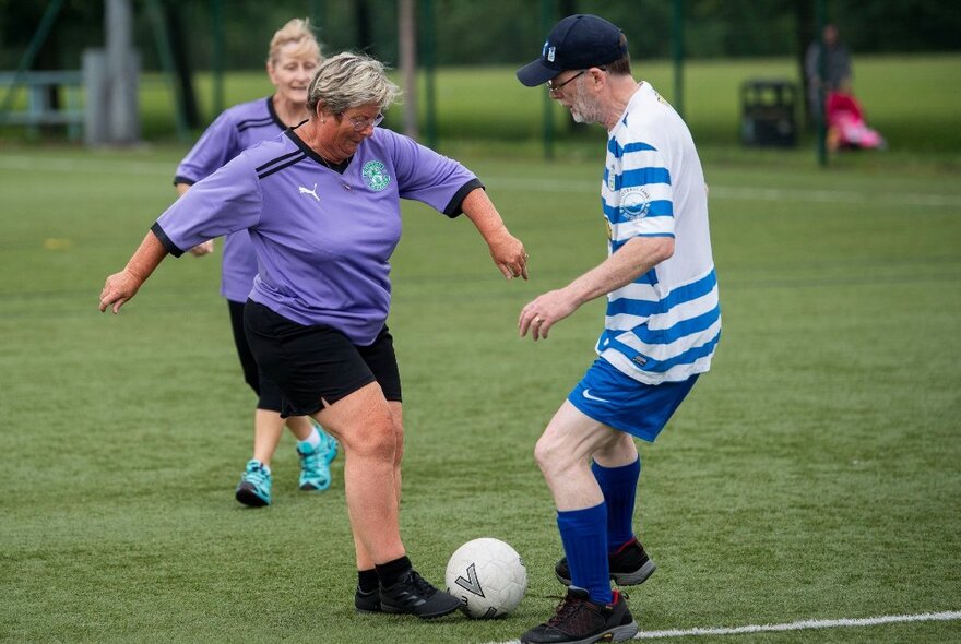 People playing walking football with two players competing for the soccerball.