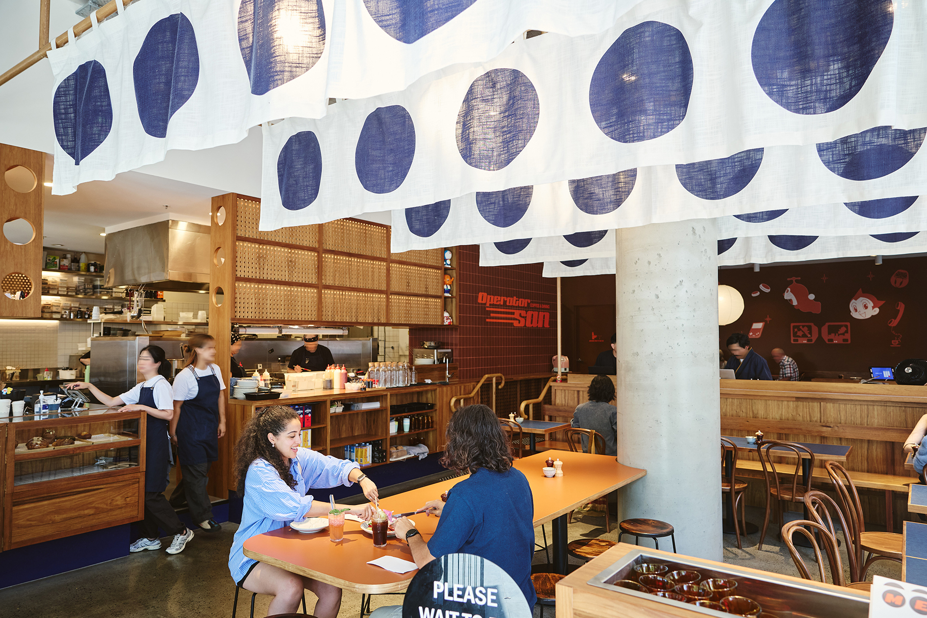 A couple dining in a cafe under white flags with blue circles.