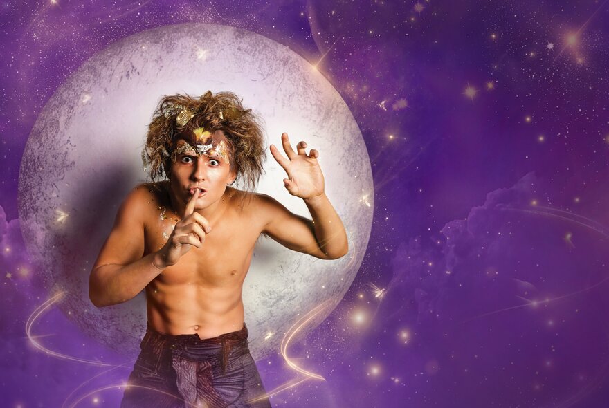 A performer dressed as Puck from A Midsummer Night's Dream, shirtless and standing in front of a purple celestial sky with a large moon as he makes the 'shh' gesture.