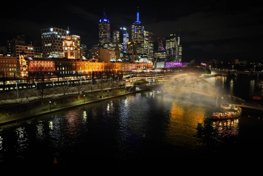 A misty art installation on the Evan Walker Bridge, part of the Now or Never festival, with a view of the Yarra river and Melbourne city skyline at night.