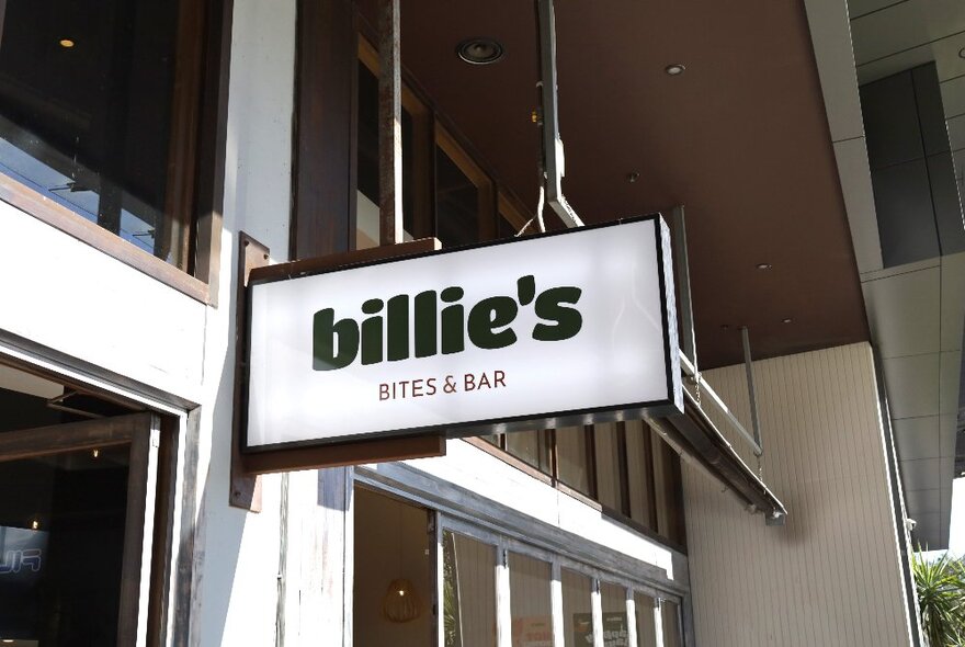 Billie's Bites & Bar outdoor signage, black text on a white background, hanging in front of door and window.