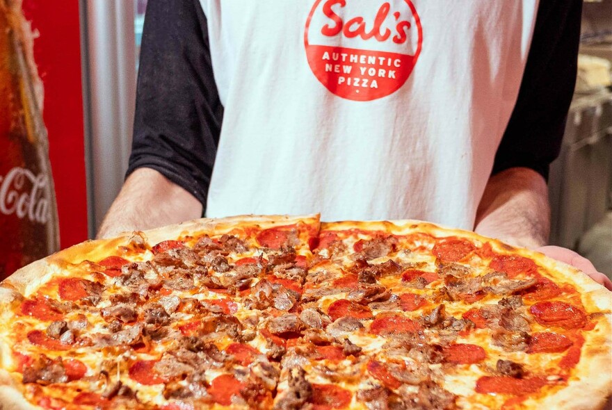 Waiter holding extra large pizza.