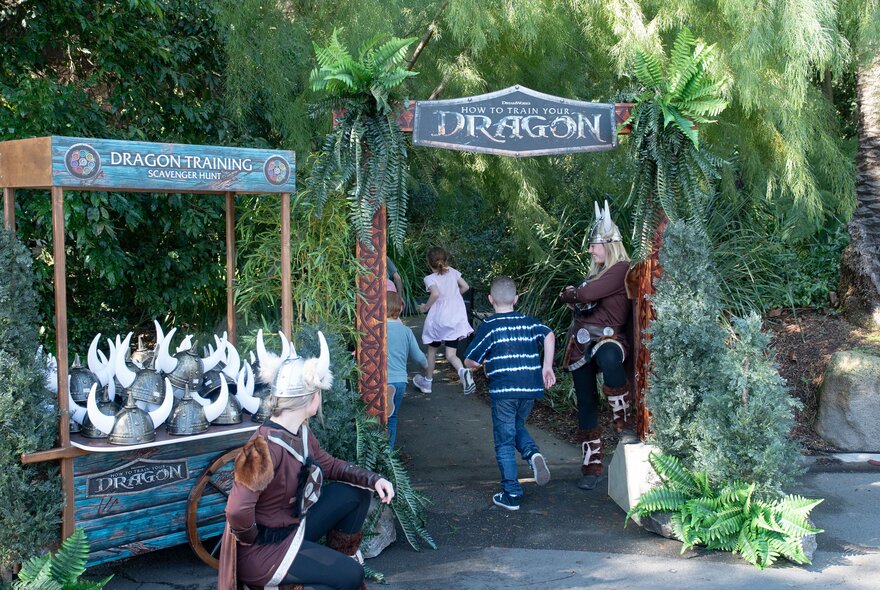 Kids enteringn a pathway labelled 'Dragon' with a cart nearly that holds Viking helmets.