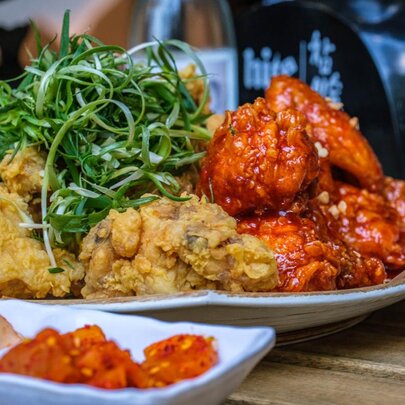 A plate of Korean fried chicken, served  with condiments, on a wooden table in a restaurant.