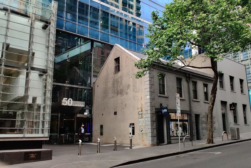 Victorian-era row of two-storeyed terrace houses backed by glass and steel office buildings.