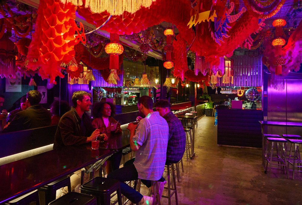 A group of people are  in a karaoke bar drinking cocktails.